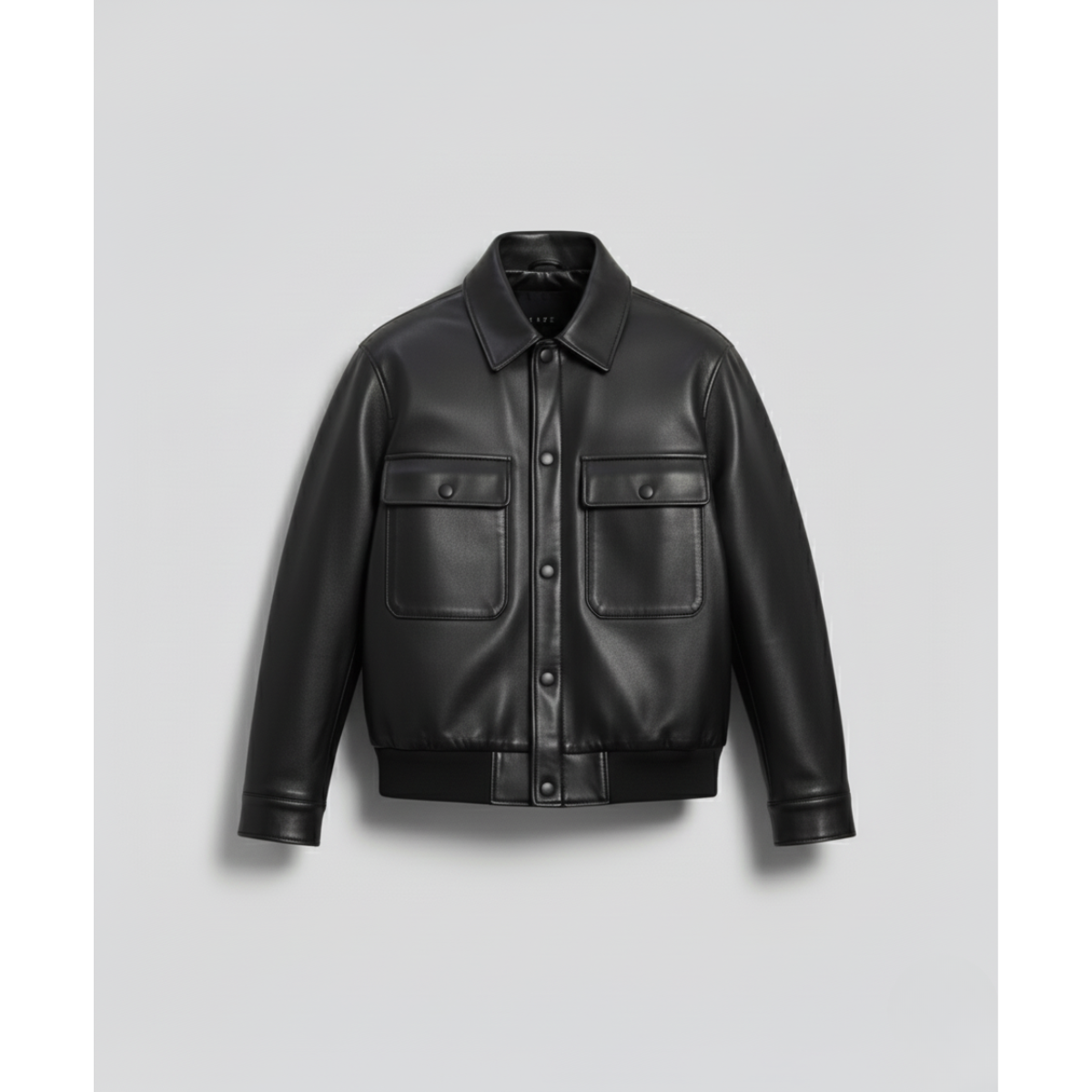 Front view of The Commander's Field Bomber Leather Jacket, a high-quality black Bomber Leather Jacket with a shirt collar, button closure, and two large, structured, button-flap patch pockets on the chest/waist, evoking a field jacket aesthetic.